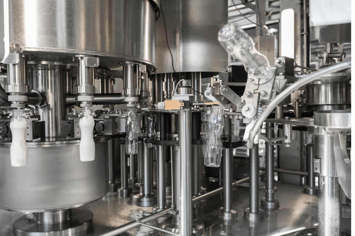Industrial process equipment for bottling, featuring automated machinery with plastic bottles and stainless steel components, relevant to process engineering consulting for manufacturing efficiency.